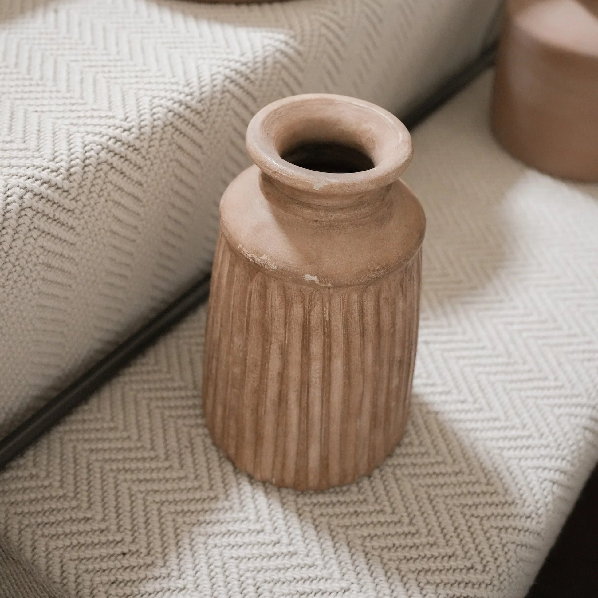 Terracotta vases on a textured surface with a mirror reflection.
