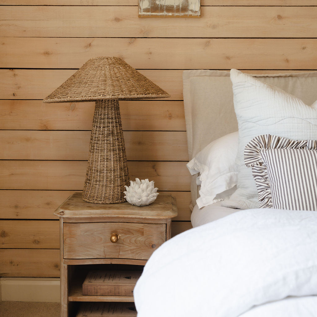 Bedroom with wooden nightstand and wicker lamp against a wooden wall.