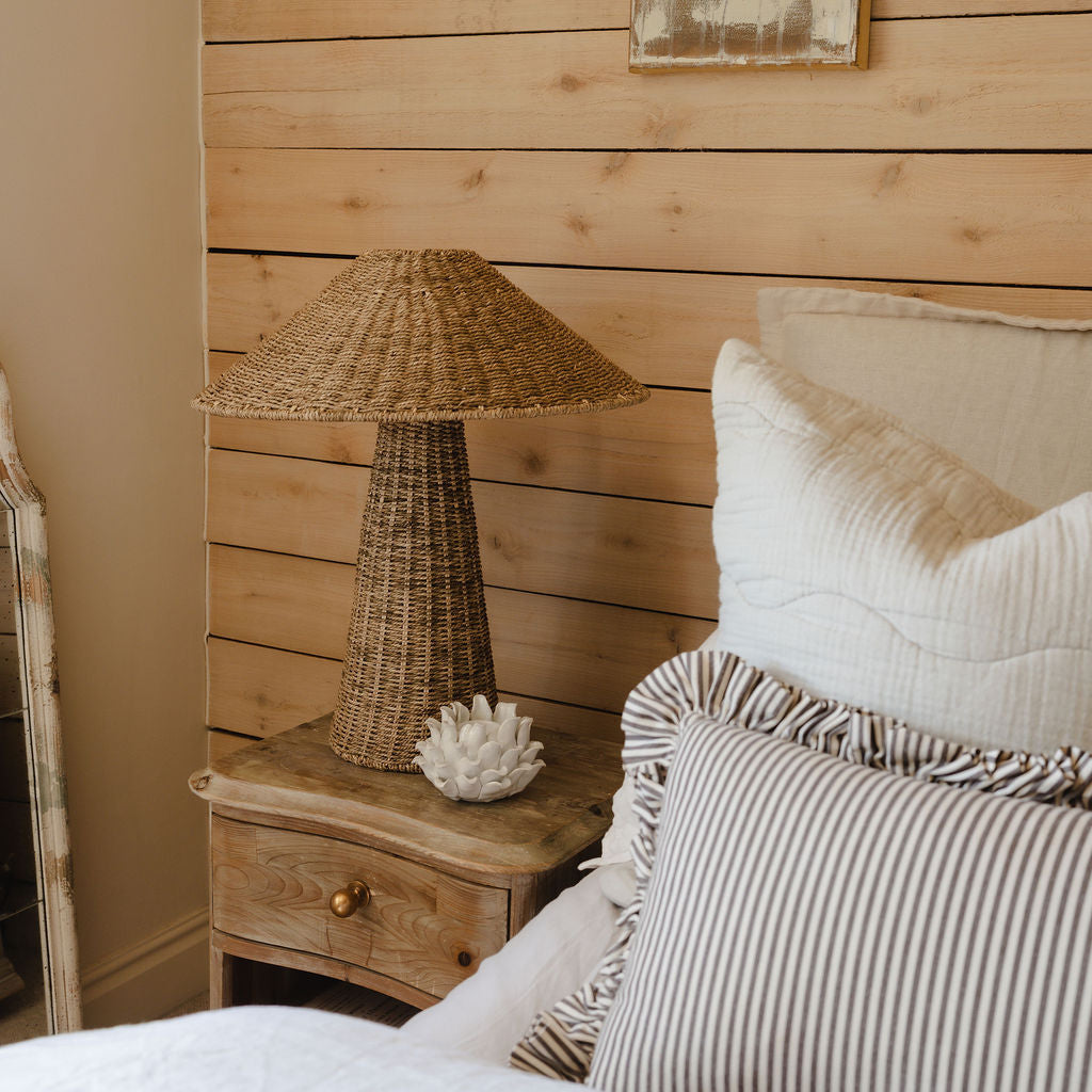 Bedroom with wooden nightstand, wicker lamp, and textured wall.