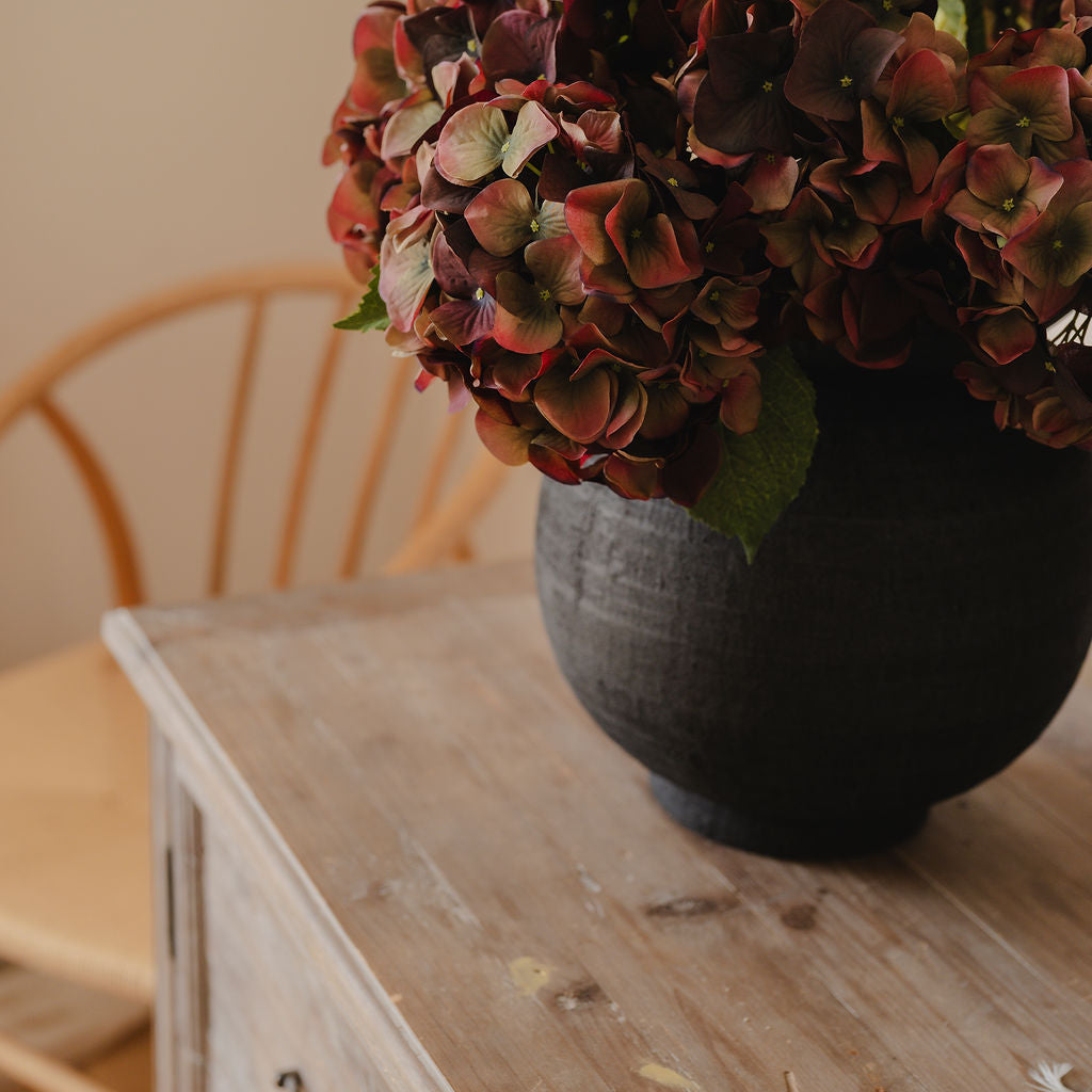 Black vase with hydrangeas on a wooden table