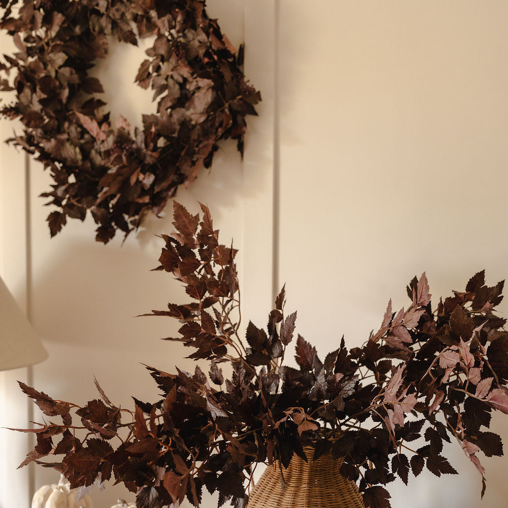 Decorative wreath and branches on a wooden surface with pumpkins