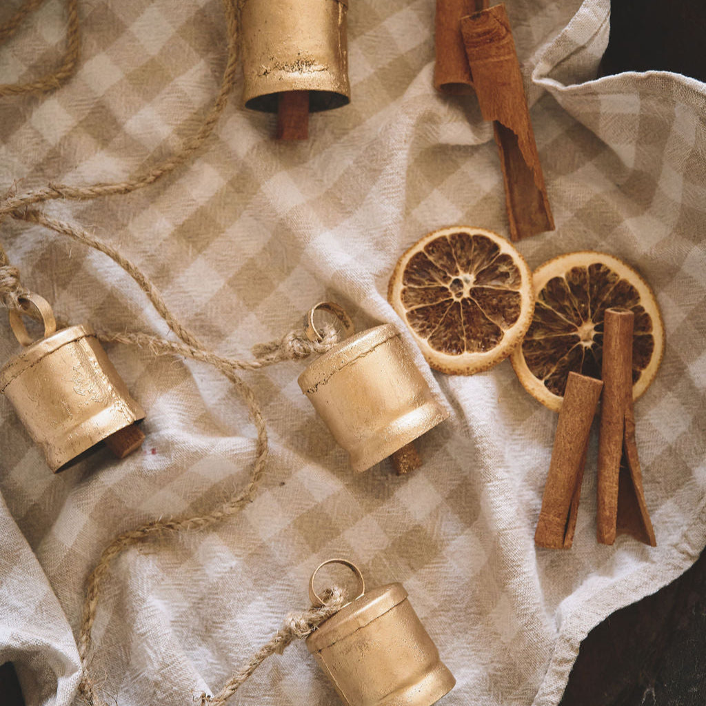 Decorative garland with small bells and dried oranges on a checkered fabric background