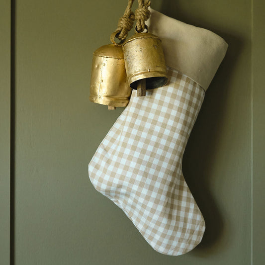 Checkered stocking with gold bells hanging on a green door