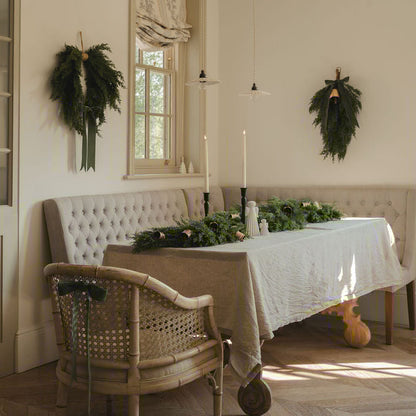 Dining room with a table set for a meal, decorated with greenery and candles.