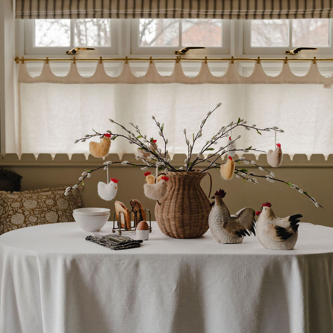 Dining room with a table set for Easter, featuring decorative eggs and branches.