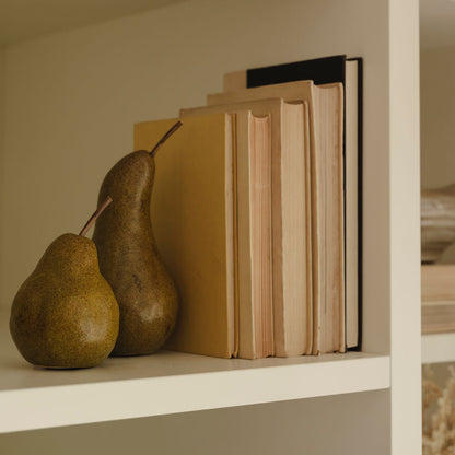 Ceramic pears styled on shelf with faux foliage and books
