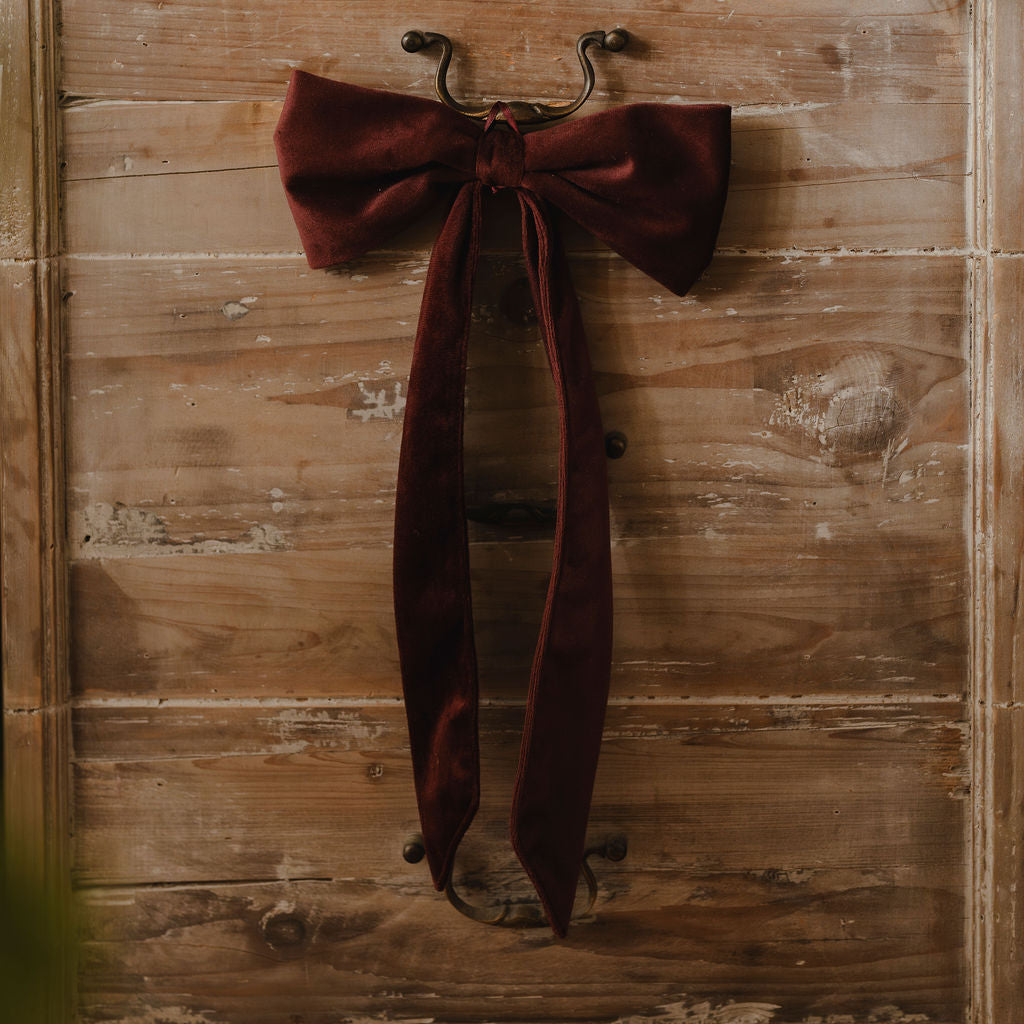 Burgundy bow tie hanging on a wooden door