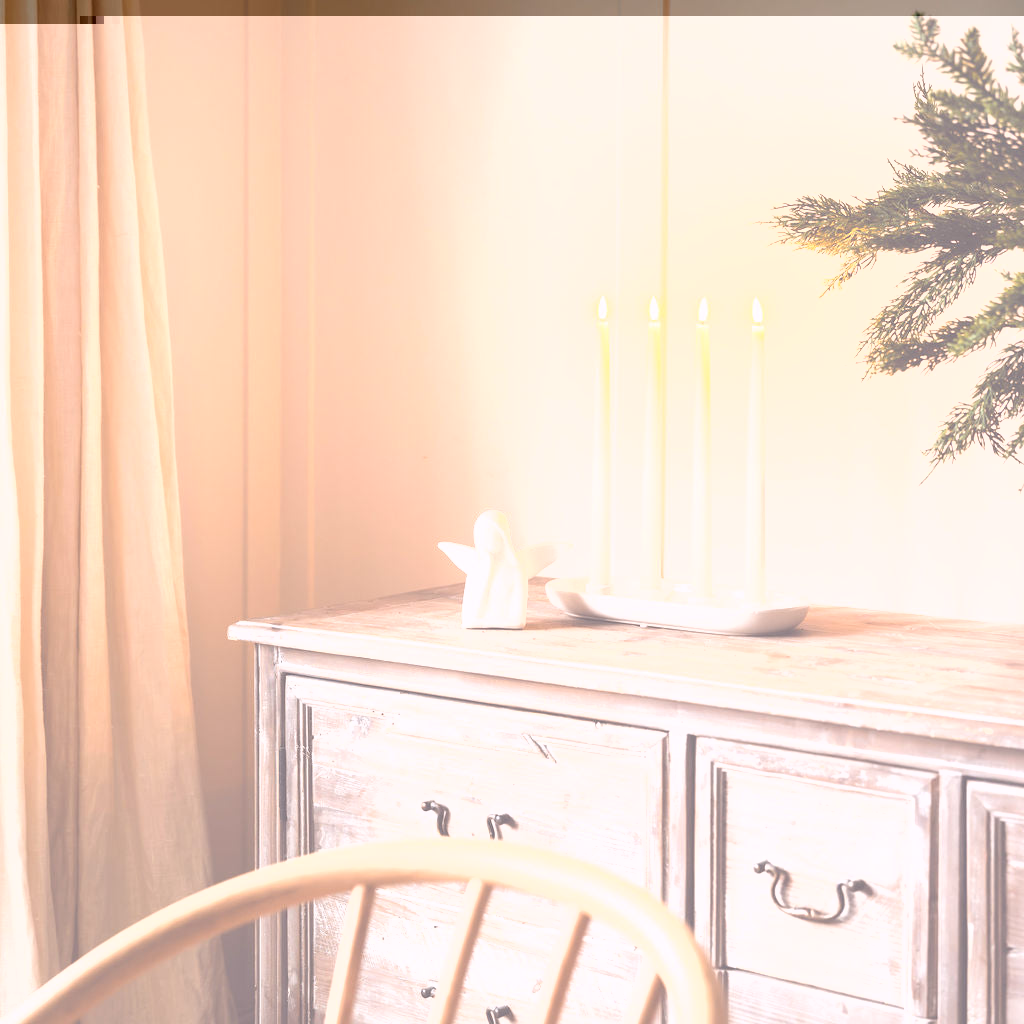 Wooden dresser with candles and a decorative angel on a neutral background
